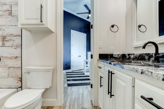 bathroom featuring a bathing tub, wood-type flooring, vanity, ceiling fan, and toilet