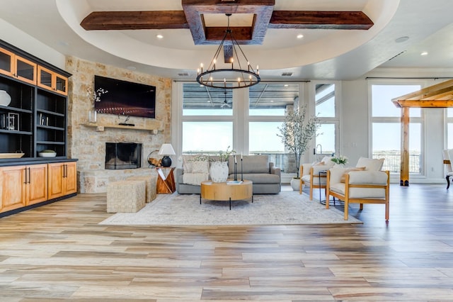 living room with a stone fireplace, a chandelier, beam ceiling, and light hardwood / wood-style flooring