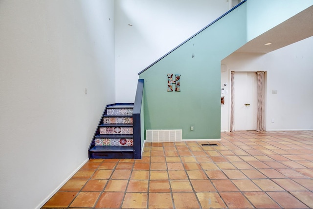 staircase with a high ceiling and tile patterned floors