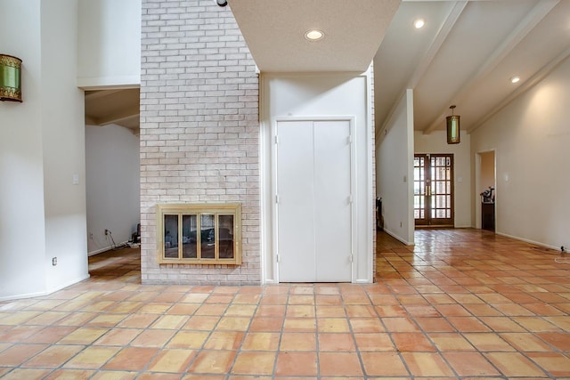 unfurnished living room featuring lofted ceiling with beams, light tile patterned flooring, and a brick fireplace