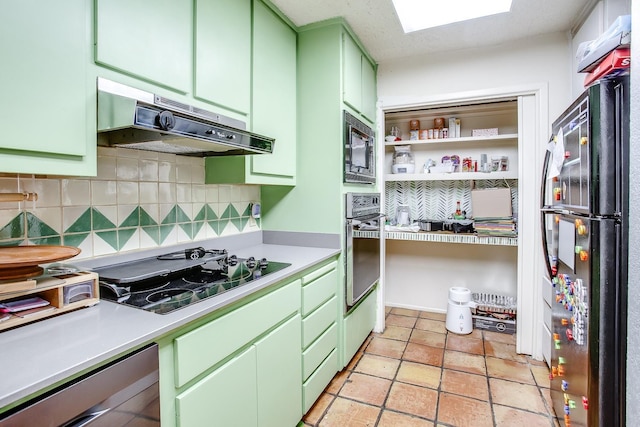 kitchen featuring built in microwave, oven, green cabinetry, gas stovetop, and black fridge