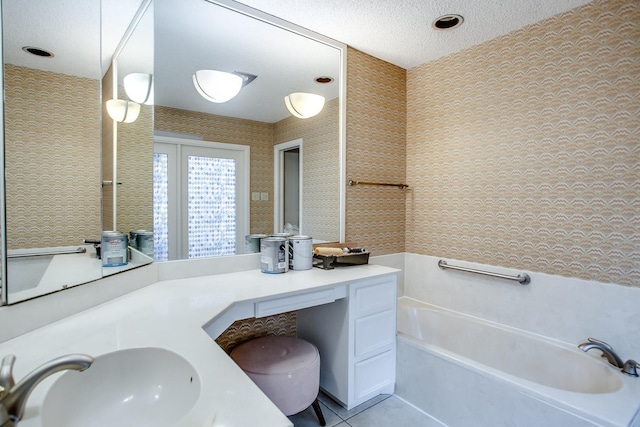 bathroom with tile patterned flooring, vanity, a washtub, and a textured ceiling