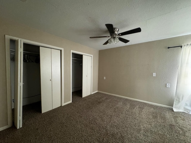 unfurnished bedroom featuring multiple closets, ceiling fan, a textured ceiling, and dark carpet