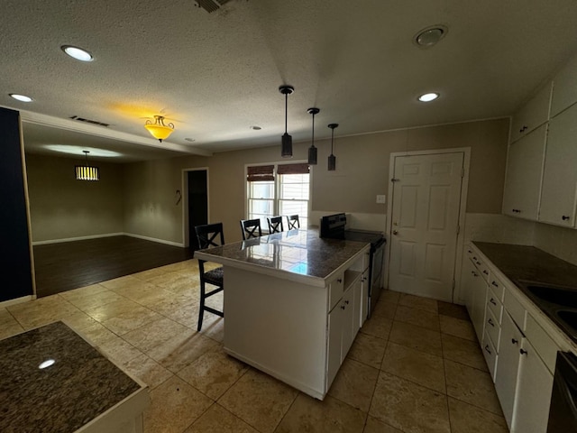 kitchen featuring pendant lighting, black appliances, white cabinets, a kitchen bar, and kitchen peninsula