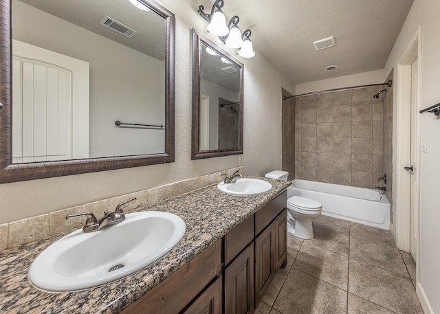 full bathroom with tiled shower / bath combo, vanity, toilet, tile patterned floors, and a textured ceiling