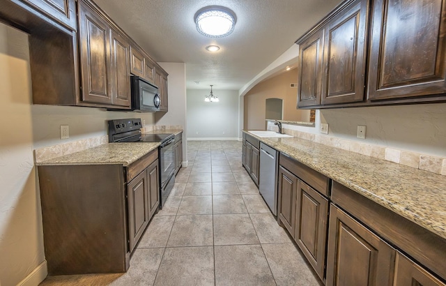 kitchen with pendant lighting, sink, light stone counters, black appliances, and dark brown cabinets