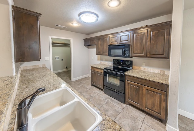 kitchen featuring sink, light stone counters, black appliances, dark brown cabinets, and a textured ceiling