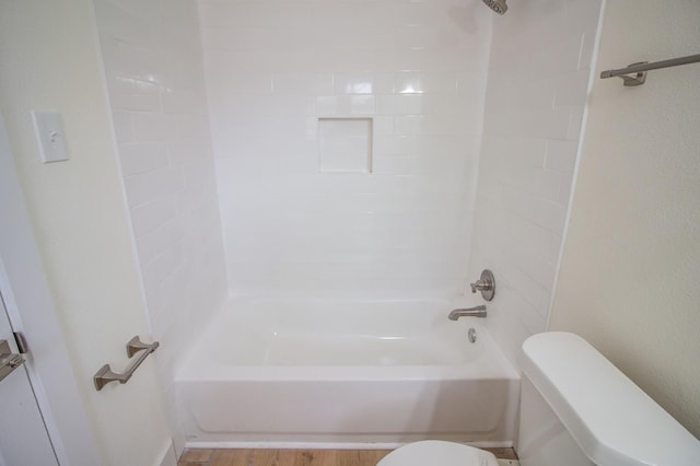 bathroom featuring hardwood / wood-style flooring, tiled shower / bath, and toilet