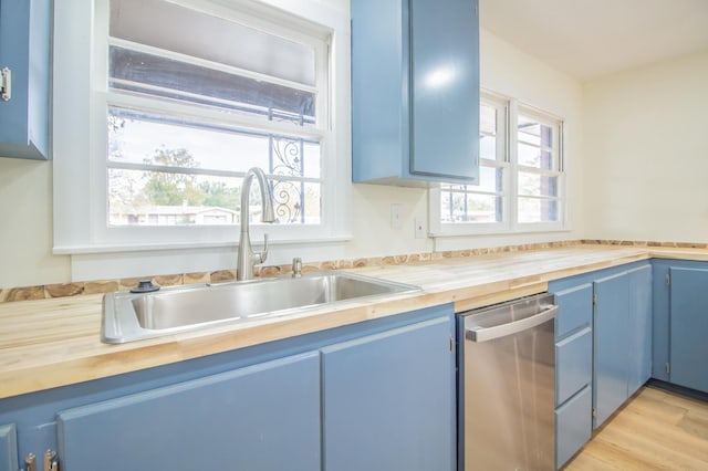 kitchen featuring sink, stainless steel dishwasher, wooden counters, and blue cabinets