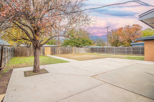 patio terrace at dusk featuring a yard