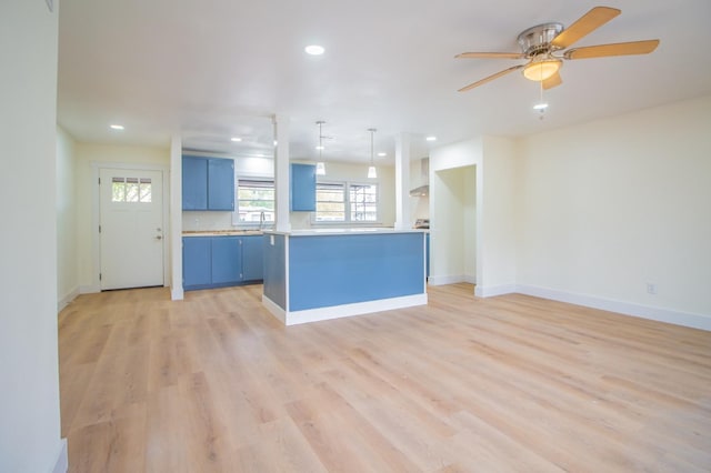 kitchen featuring blue cabinetry, decorative light fixtures, a kitchen island, ceiling fan, and light hardwood / wood-style floors