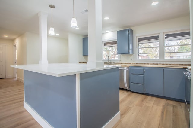 kitchen featuring blue cabinets, sink, decorative light fixtures, light wood-type flooring, and stainless steel dishwasher