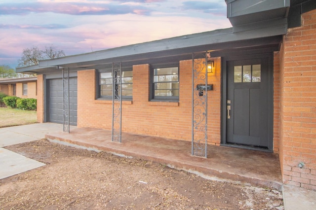 exterior entry at dusk featuring a garage