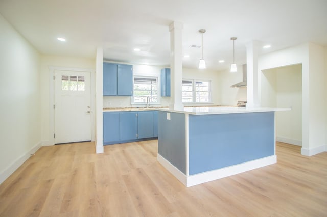 kitchen featuring blue cabinets, kitchen peninsula, light hardwood / wood-style floors, and hanging light fixtures