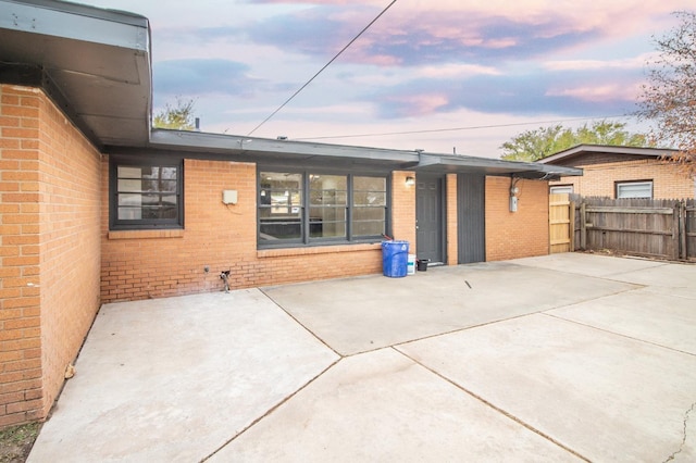 back house at dusk featuring a patio