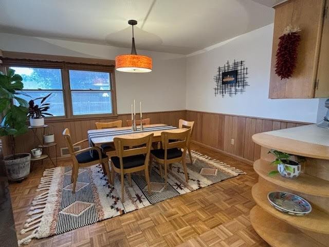 dining space featuring light parquet flooring and wood walls