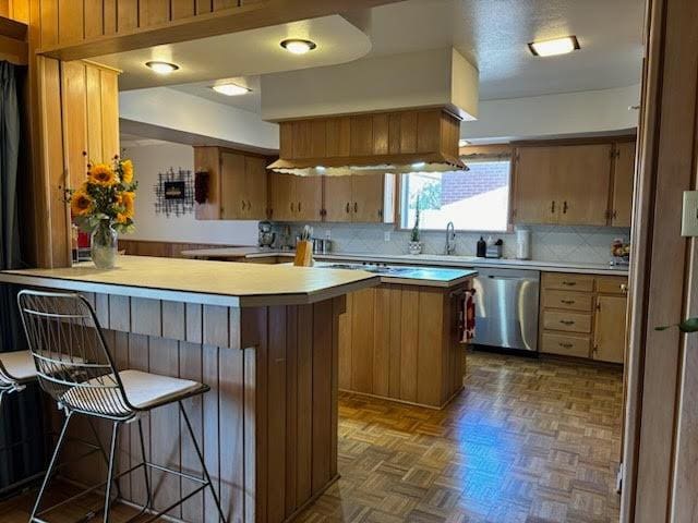 kitchen featuring dark parquet floors, dishwasher, a kitchen bar, a center island, and kitchen peninsula