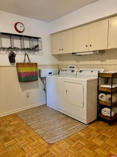 laundry area featuring washer and dryer, cabinets, and light parquet flooring