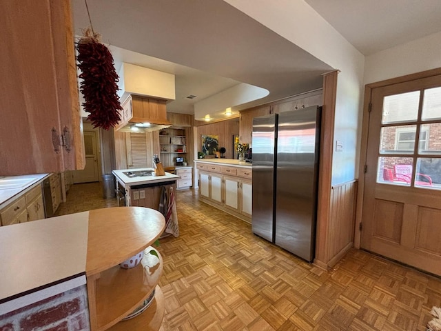 kitchen featuring light parquet floors, a kitchen island, a healthy amount of sunlight, and stainless steel refrigerator