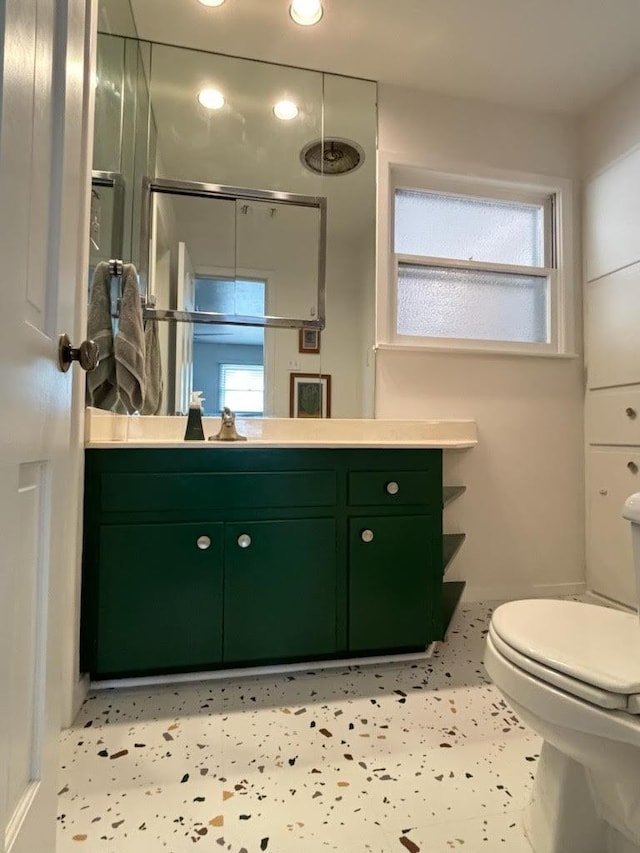 bathroom featuring tile patterned flooring, vanity, toilet, and walk in shower