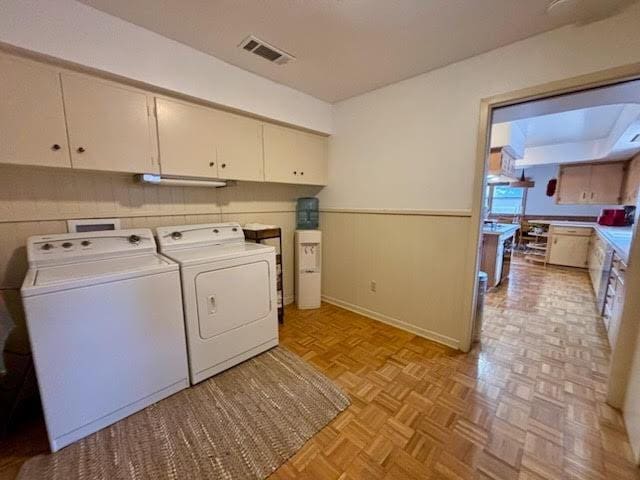 laundry area featuring cabinets, light parquet flooring, and washer and dryer