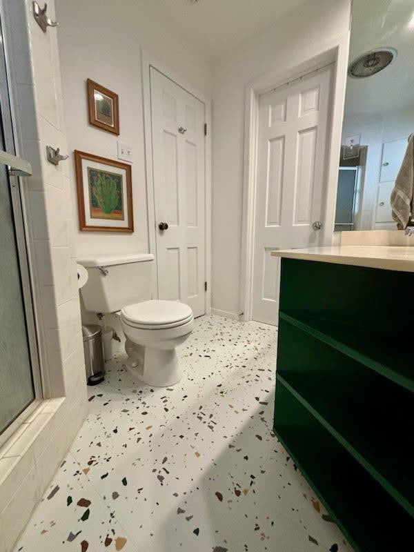 bathroom featuring vanity, a shower with shower door, and toilet