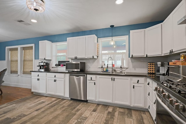 kitchen featuring sink, white cabinetry, decorative light fixtures, appliances with stainless steel finishes, and dark hardwood / wood-style floors