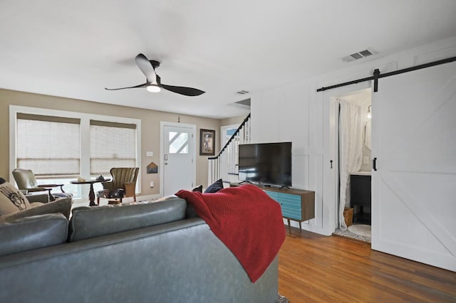 living room featuring hardwood / wood-style flooring, ceiling fan, and a barn door