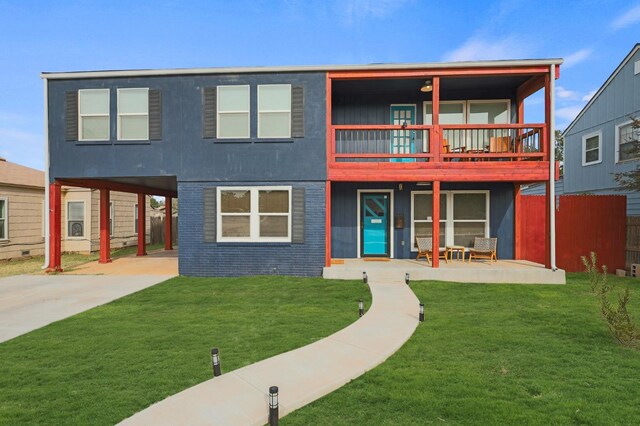 back of property with a patio, a balcony, and a lawn