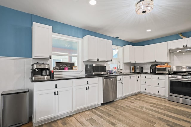 kitchen featuring appliances with stainless steel finishes, sink, hanging light fixtures, and white cabinets