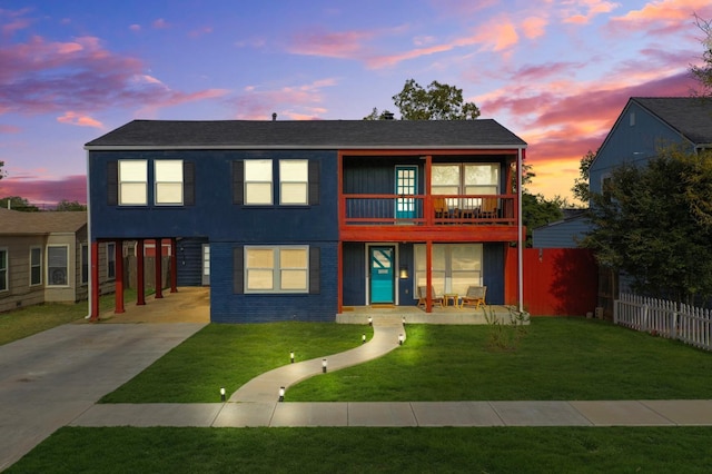 view of front facade featuring a balcony and a lawn