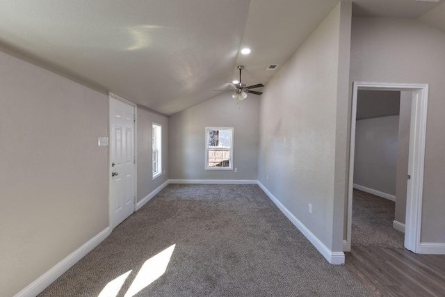 interior space featuring ceiling fan, lofted ceiling, and dark colored carpet