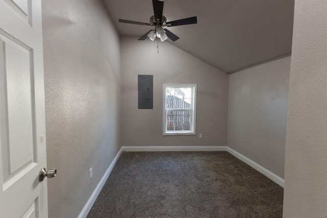 spare room featuring ceiling fan, electric panel, vaulted ceiling, and dark colored carpet