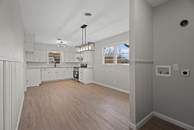 kitchen with white cabinetry, plenty of natural light, light hardwood / wood-style floors, stainless steel range oven, and decorative light fixtures