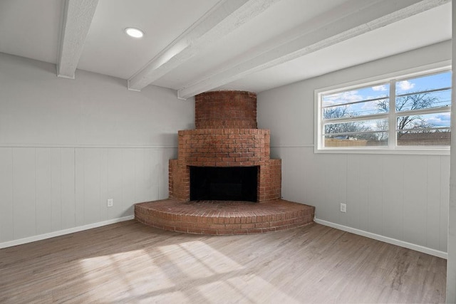 unfurnished living room featuring hardwood / wood-style flooring, a fireplace, and beam ceiling