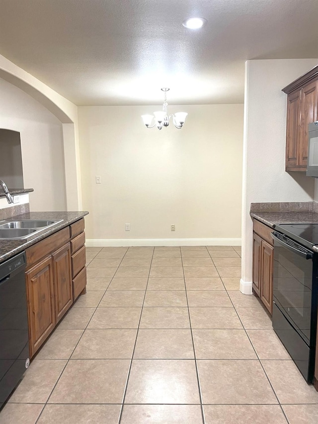 kitchen with light tile patterned floors, dark countertops, black appliances, a chandelier, and a sink