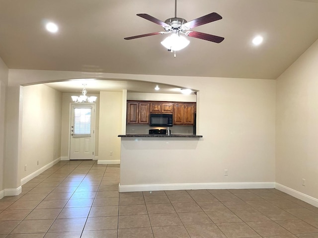 kitchen featuring lofted ceiling, light tile patterned floors, ceiling fan with notable chandelier, and kitchen peninsula