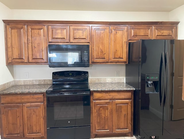 kitchen featuring dark stone counters and black appliances