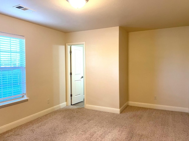 spare room with visible vents, light carpet, and baseboards