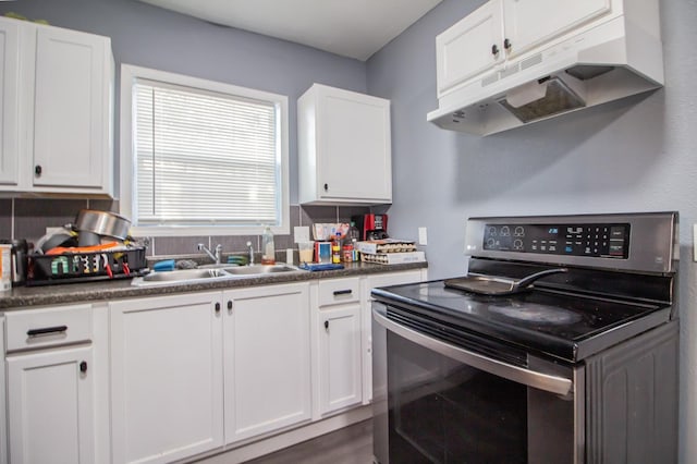 kitchen featuring tasteful backsplash, stainless steel range with electric stovetop, sink, and white cabinets