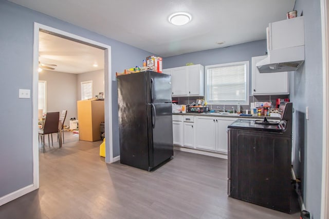 kitchen with black refrigerator, white cabinetry, ceiling fan, and light hardwood / wood-style floors