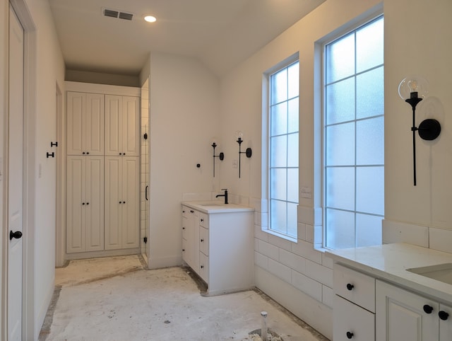 full bath with two vanities, visible vents, and unfinished concrete floors