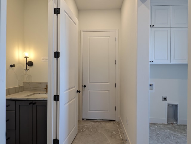 interior space featuring cabinet space, baseboards, hookup for a washing machine, hookup for an electric dryer, and a sink