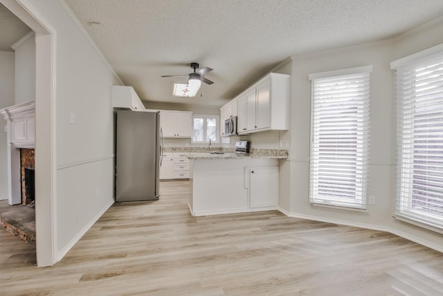 kitchen featuring white cabinetry, a fireplace, stainless steel appliances, and a textured ceiling