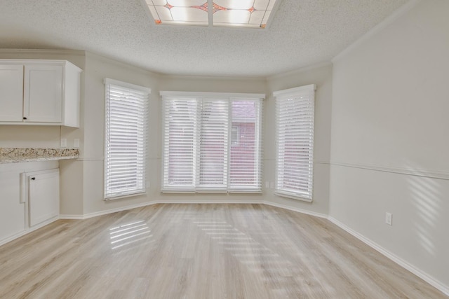 unfurnished dining area with crown molding, light hardwood / wood-style flooring, and a textured ceiling