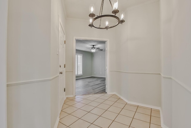 hall featuring crown molding, light tile patterned floors, and a notable chandelier