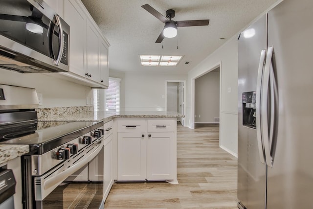 kitchen featuring stainless steel appliances, light stone countertops, kitchen peninsula, and white cabinets