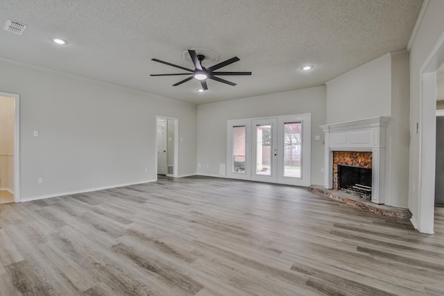 unfurnished living room with ceiling fan, ornamental molding, a textured ceiling, and light hardwood / wood-style flooring