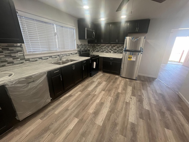 kitchen with stainless steel appliances, sink, light wood-type flooring, and decorative backsplash