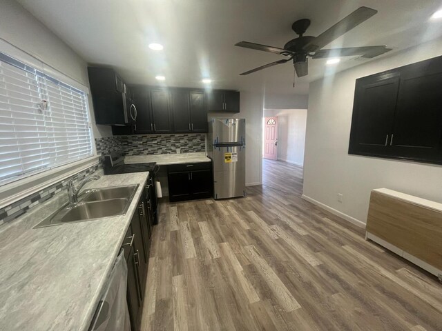 kitchen featuring sink, light hardwood / wood-style flooring, ceiling fan, appliances with stainless steel finishes, and decorative backsplash